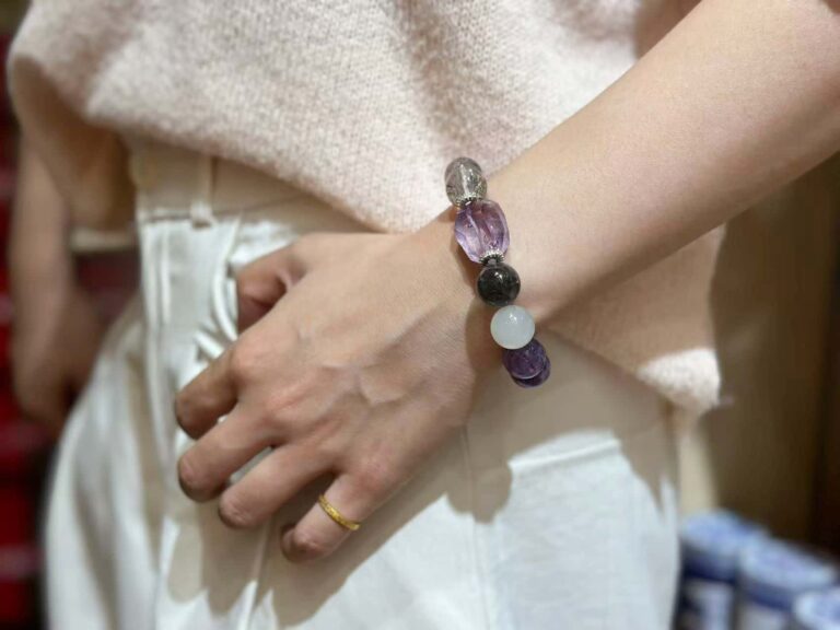 Close-up of amethyst bracelet with deep purple crystals in natural light, showing unique color zoning and clarity